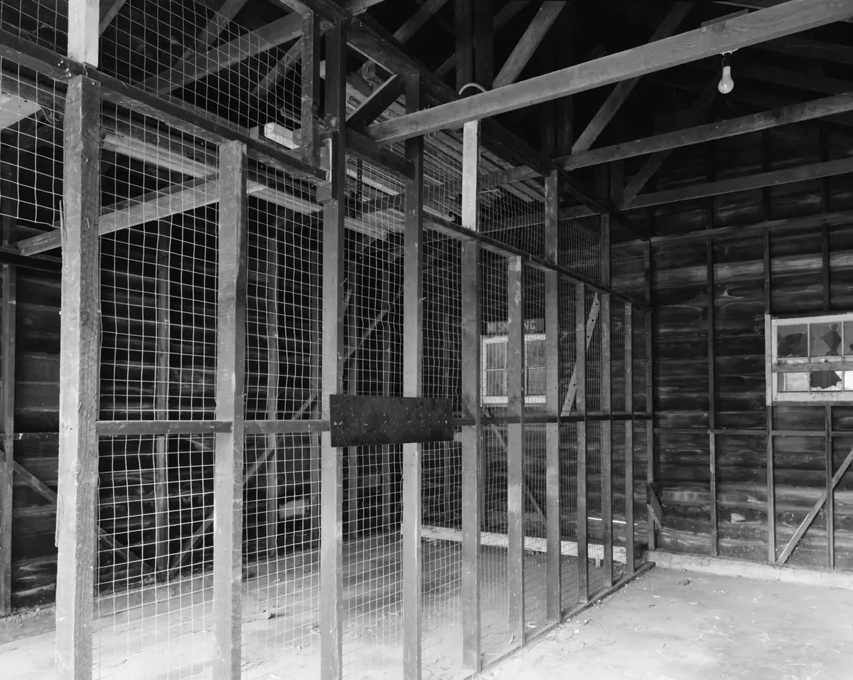 An older two-bay garage with exposed framing and a wire partition