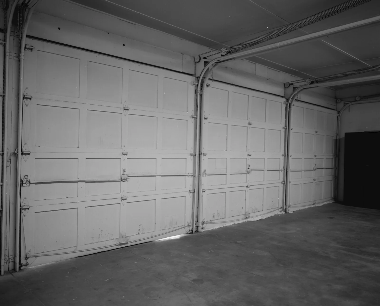 Inside a garage, looking at closed wood-panel overhead doors and their side tracks